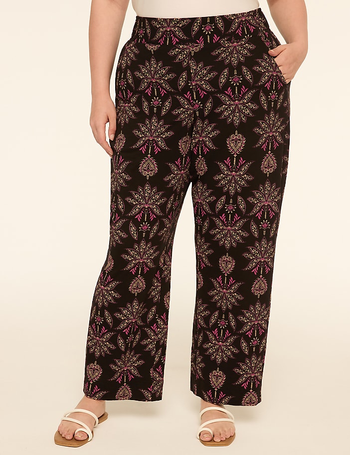A person wearing patterned pants stands against a plain, light-colored background.