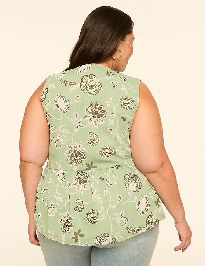 A woman in a floral peplum top stands against a plain, light-colored background.