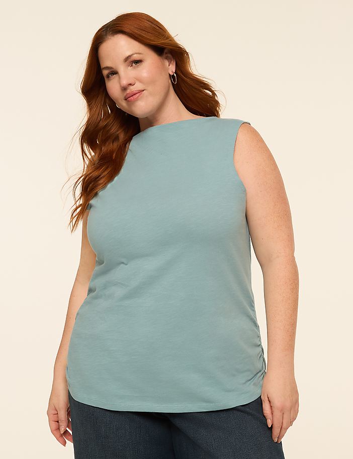A woman with red hair stands in the foreground against a plain, light-colored background.