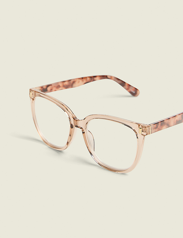 A pair of clear-lensed, tortoiseshell-patterned glasses rests on a plain, light-colored background.