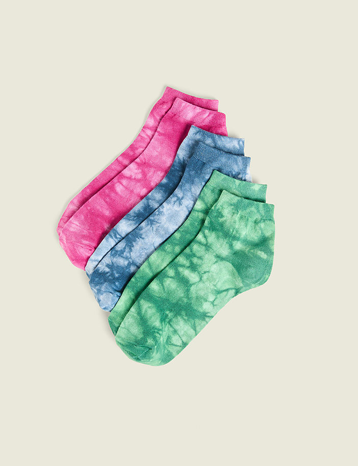 Four tie-dye ankle socks in pink, blue, and green are arranged diagonally on a plain, light-colored background.