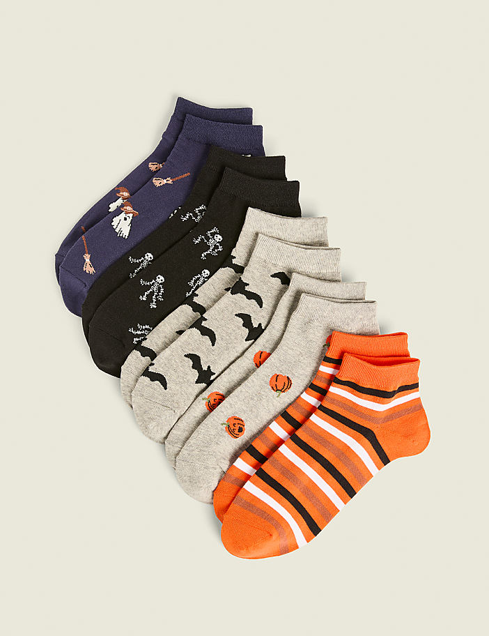 A collection of Halloween-themed ankle socks with various patterns are arranged diagonally in the foreground against a plain, light-colored background.