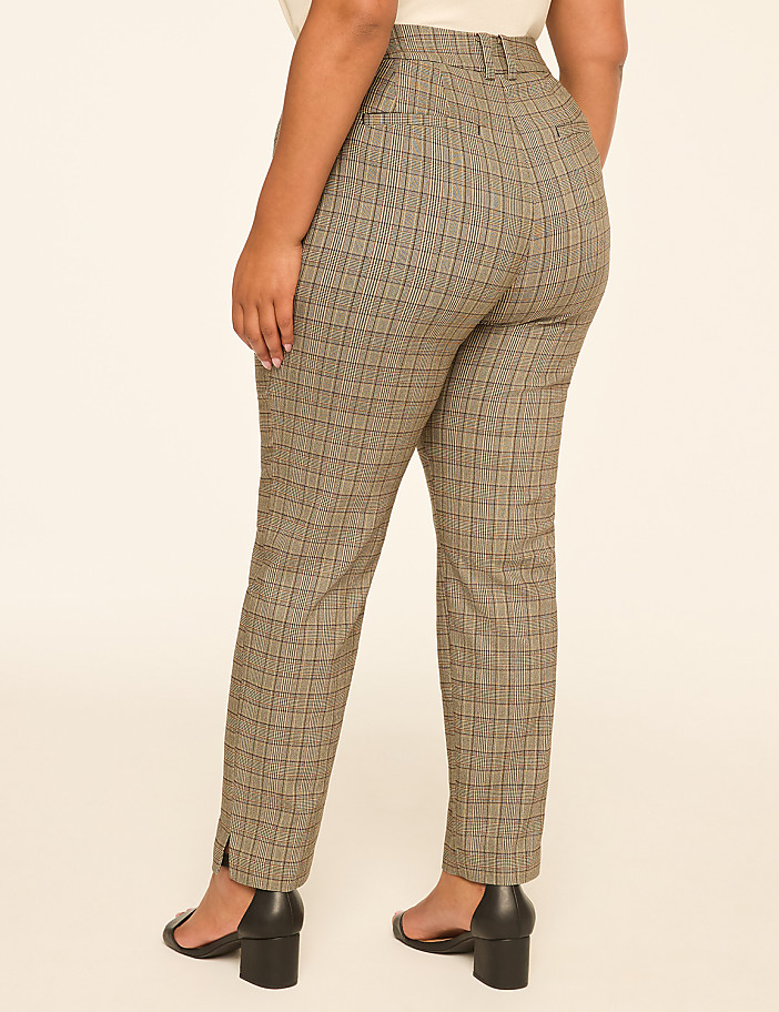 A person wearing plaid pants with a slit at the ankle stands against a plain, light-colored background.