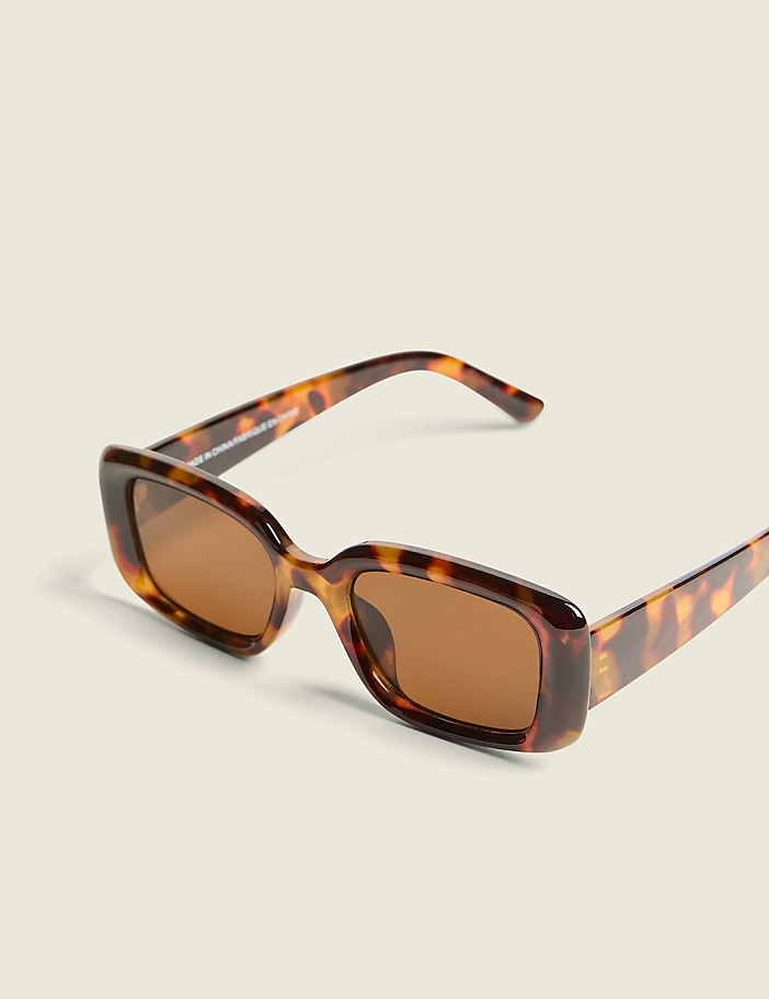 Tortoiseshell rectangular sunglasses with brown lenses rest on a plain, light-colored background.
