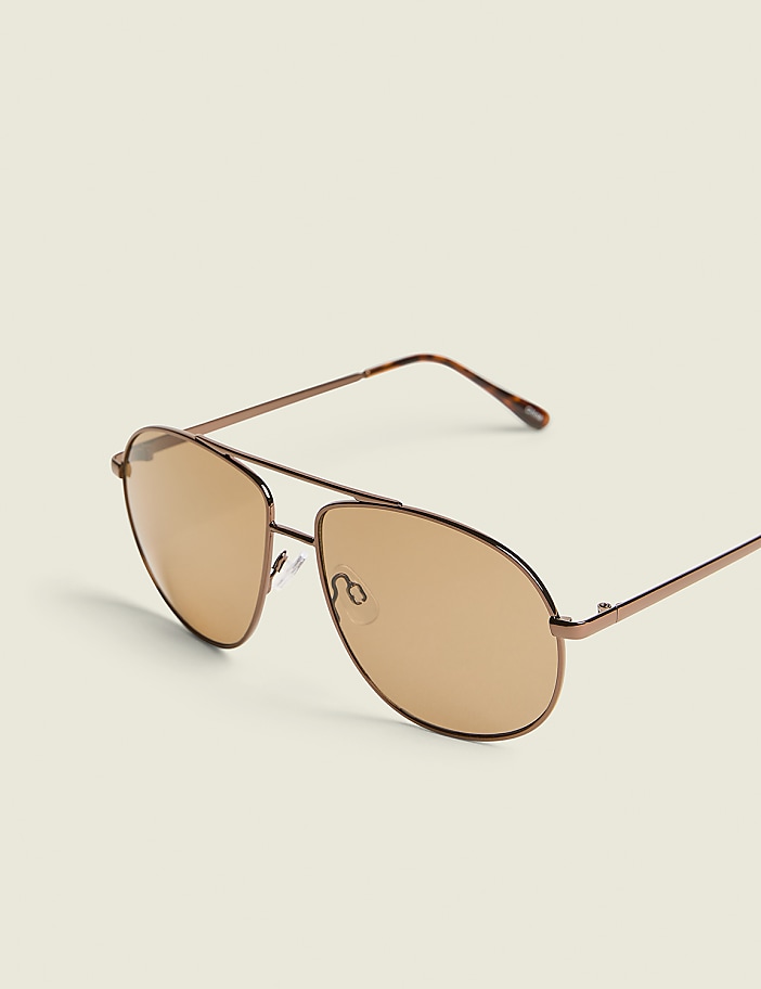 Aviator sunglasses with brown lenses rest on a plain, light-colored background.