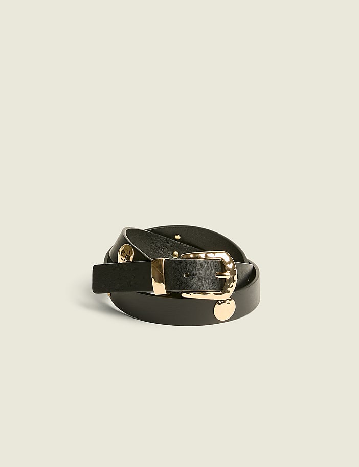 A black leather belt with a gold buckle is coiled in the foreground against a plain, light-colored background.
