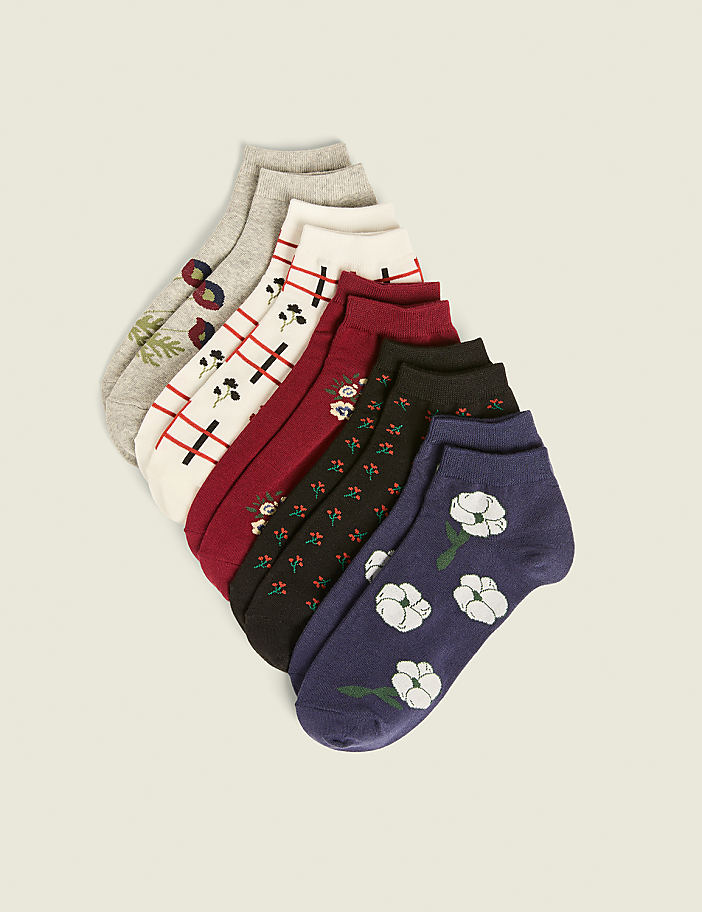 A fan of patterned ankle socks, including floral and plaid designs, is arranged on a plain, light-colored background.