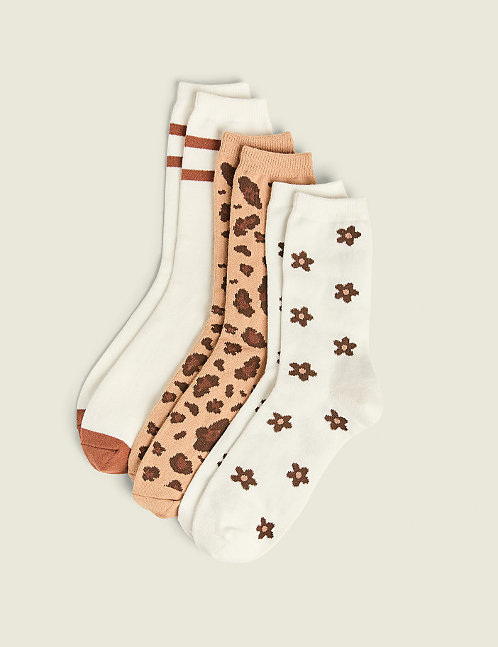 Four pairs of patterned socks, including stripes, leopard print, and flowers, are arranged on a plain, light-colored background.