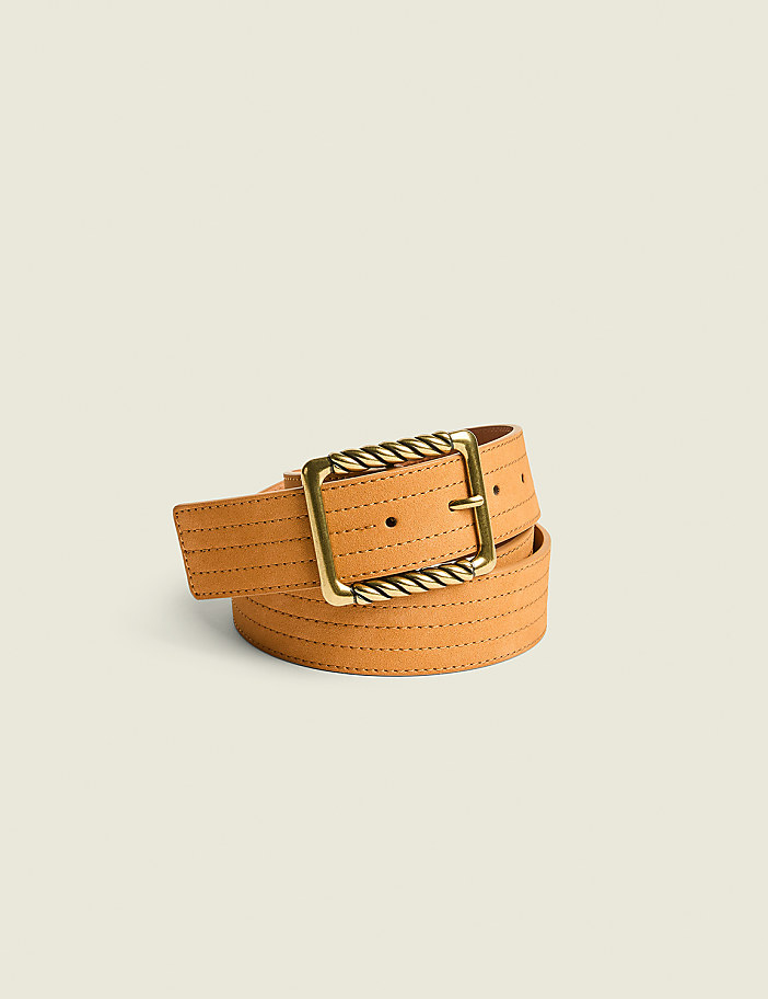 A tan leather belt with a gold buckle is laid out against a plain, light beige background.