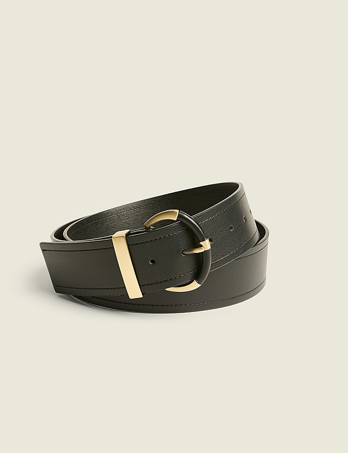 A black leather belt with a gold buckle is coiled on a plain, light-colored background.