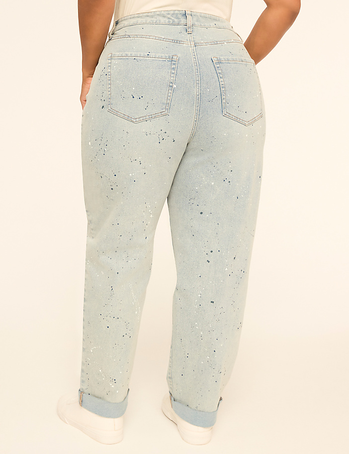A person wearing light blue, paint-splattered jeans with cuffed hems stands against a plain, light-colored background.