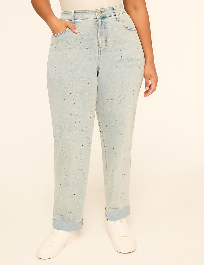 A person stands in light-wash, rhinestone-embellished jeans with cuffed ankles and white sneakers against a plain, light-colored background.