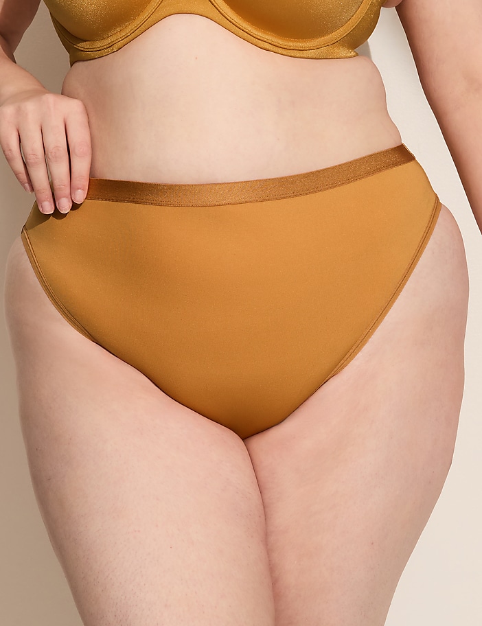 A person's torso is shown from the waist down, wearing mustard-colored underwear and a matching bra, against a plain, light-colored background.
