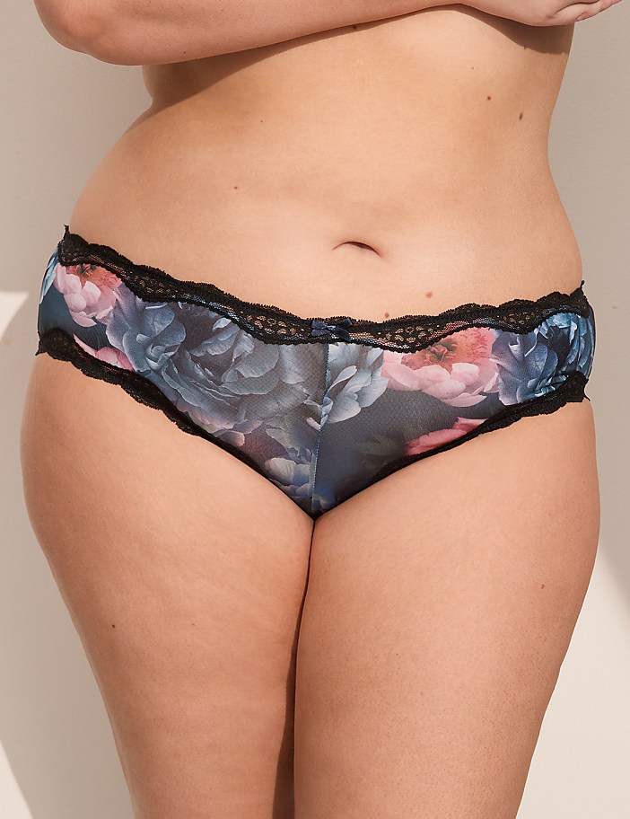 A person's midsection is adorned with floral-patterned underwear with black lace trim, set against a plain, light-colored background.