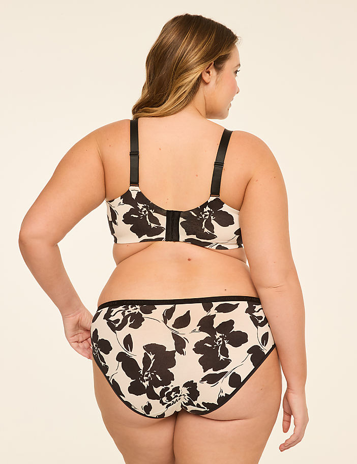 A woman in a floral bra and panties stands against a plain, light-colored background.