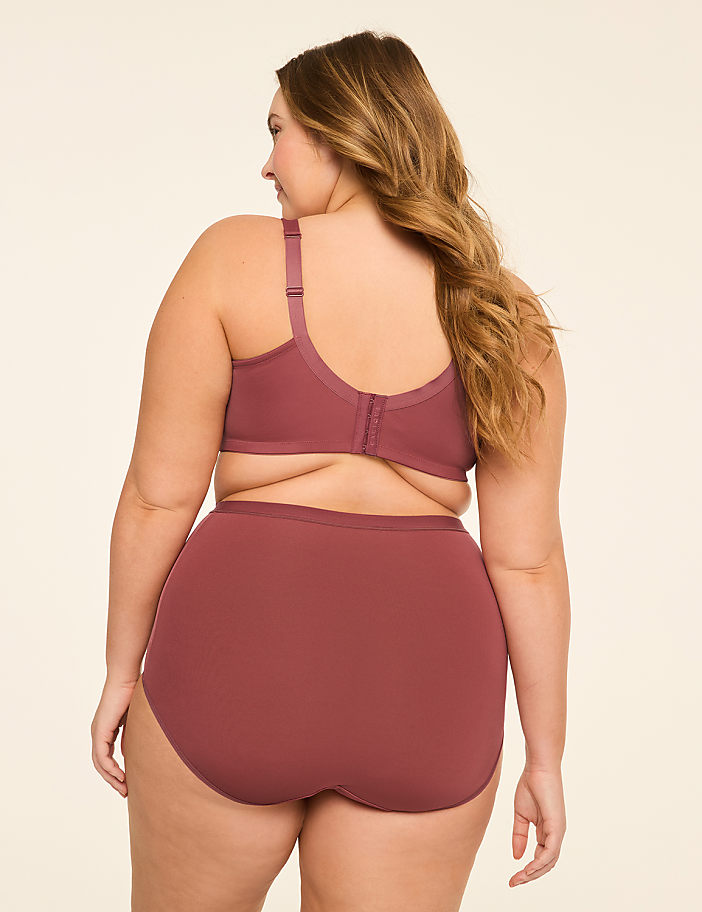 A woman in a mauve bra and high-waisted briefs stands against a plain, light-colored background.