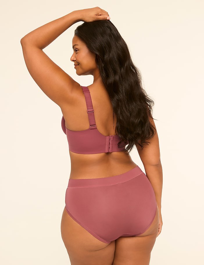 A woman in a mauve bra and underwear stands with her back to the viewer against a plain, light-colored background.