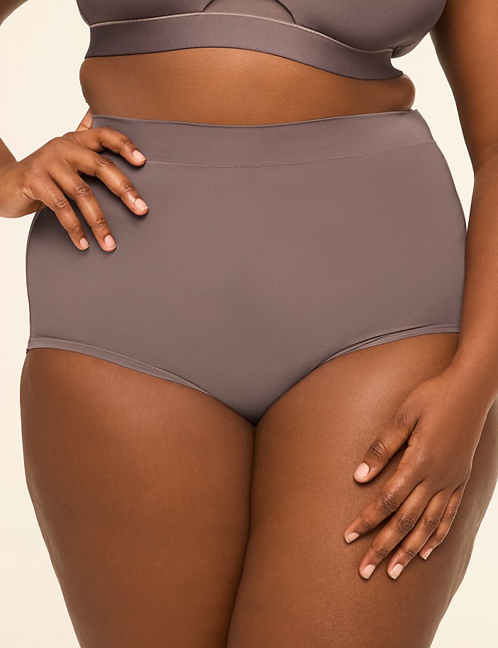 A woman in a grey bra and high-waisted underwear stands against a plain, light background.