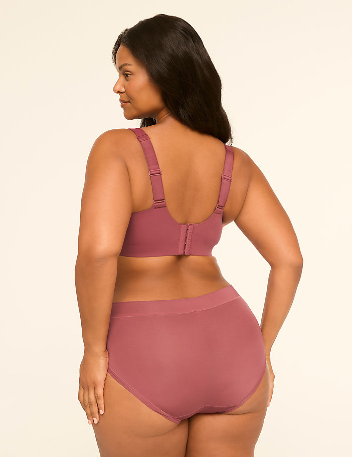 A woman in a mauve bra and underwear stands with her back to the viewer against a plain, light background.