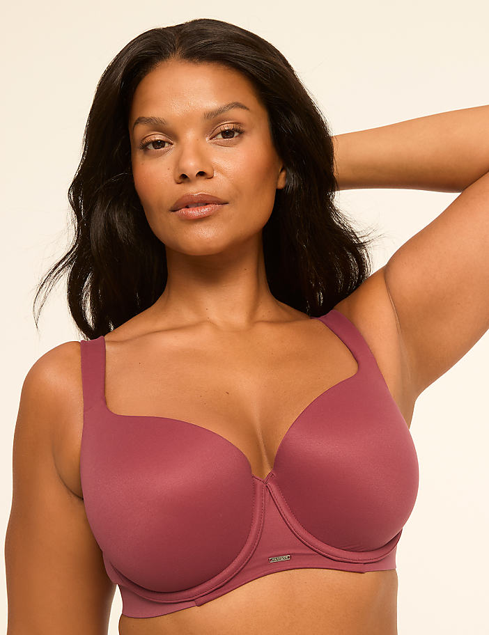 A woman in a mauve bra poses against a plain, light background.