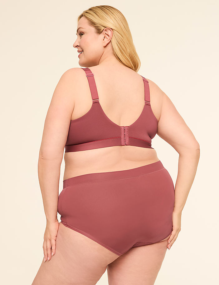 A woman in a mauve bra and underwear stands against a plain, light-colored background.