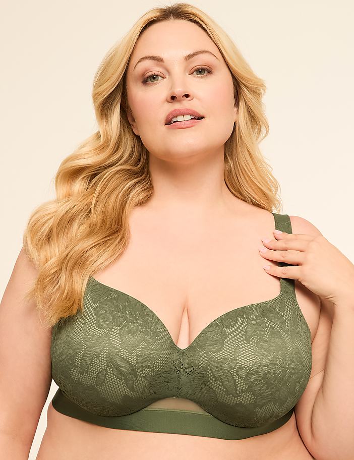 A woman with blonde hair and fair skin poses in a green lace bra against a plain, light-colored background.