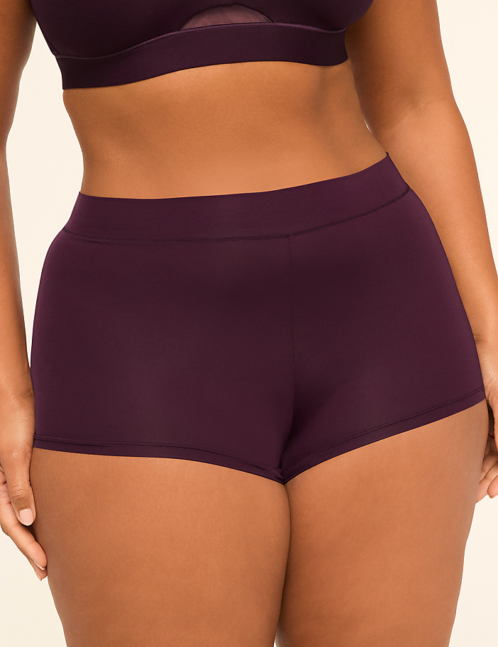 A person in dark purple underwear stands against a plain, light background.