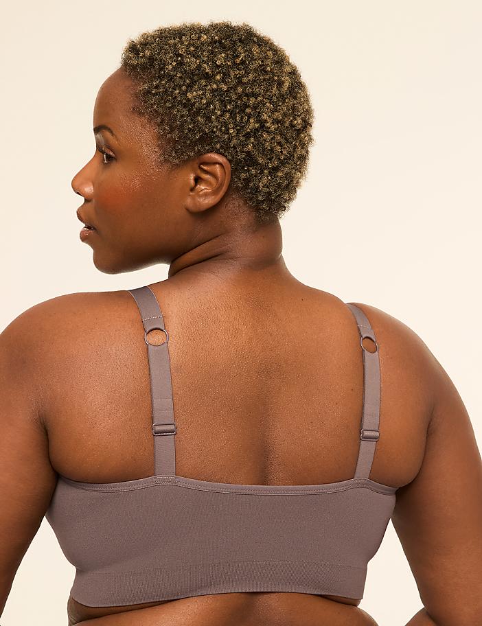 A woman with short, curly hair is shown from the back, wearing a taupe bra against a plain, light-colored background.