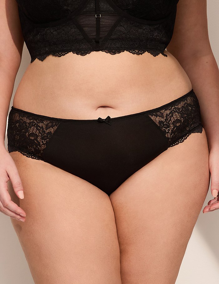 A person's midsection is shown in the foreground, wearing black lace-trimmed underwear and a black lace bra, with a plain background.