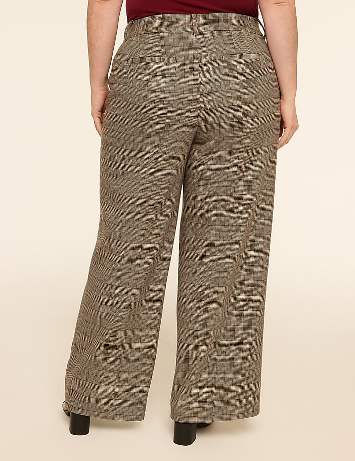 A person wearing patterned wide-leg pants stands against a plain, light-colored background.