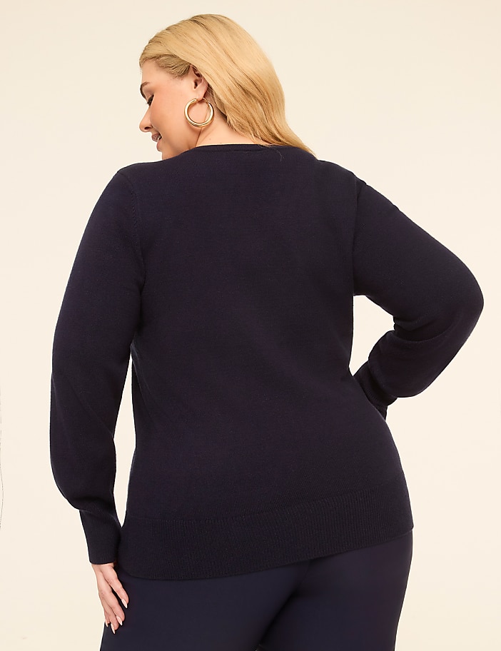 A woman in a navy sweater and pants stands against a plain, light background.