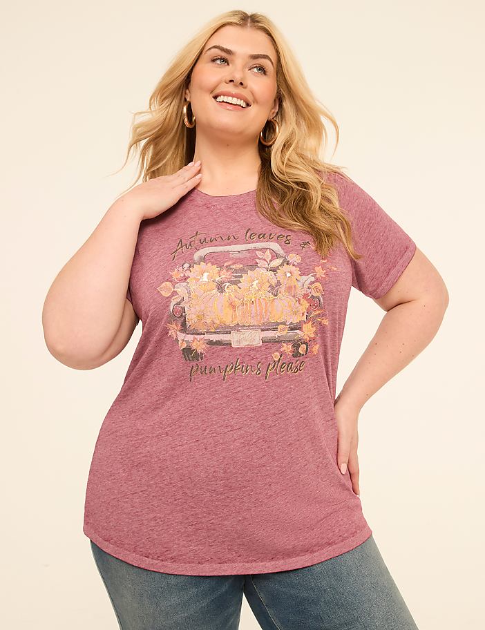 A woman in a maroon t-shirt with a fall-themed graphic stands against a plain, light-colored background.