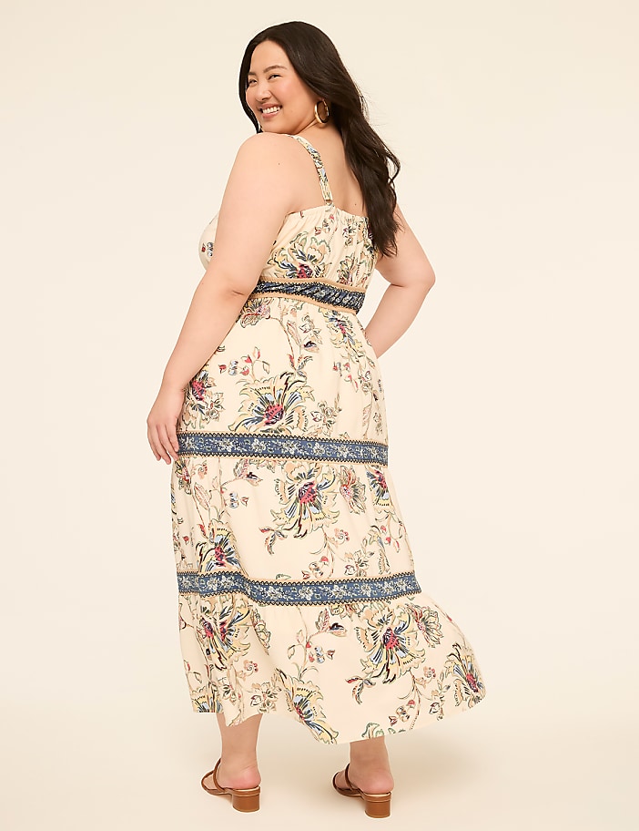 A woman in a floral print dress stands against a plain, light-colored background.