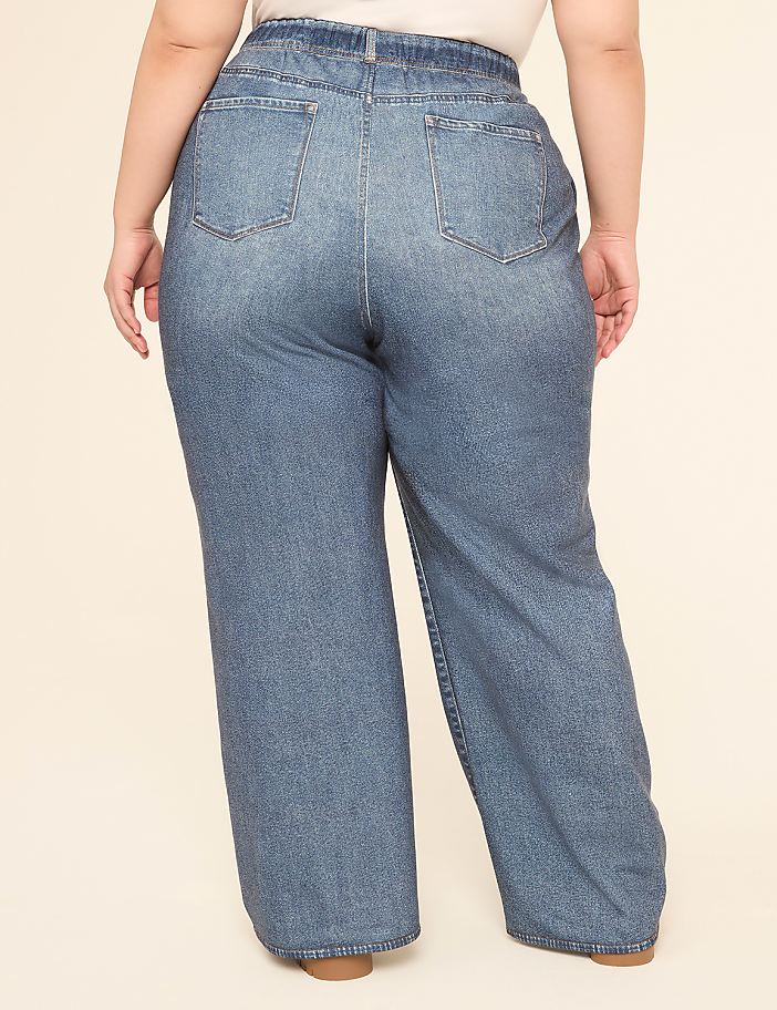 A person wearing loose-fitting denim jeans stands against a plain, light-colored background.