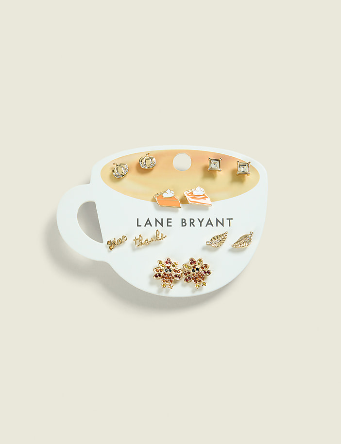 A set of fall-themed earrings, including pumpkin pie slices and leaves, are displayed on a white coffee cup-shaped card against a pale yellow background.