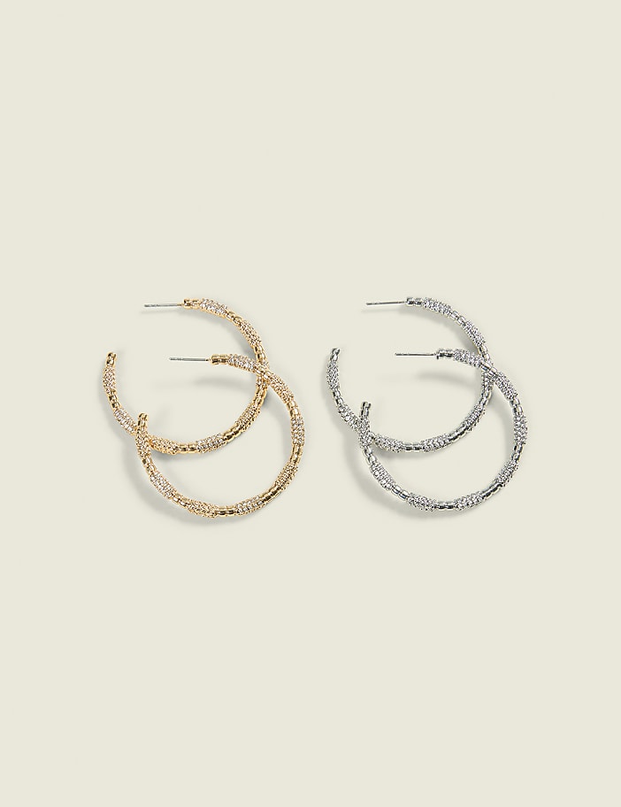 Two pairs of textured hoop earrings, one gold and one silver, are displayed against a plain, light-colored background.