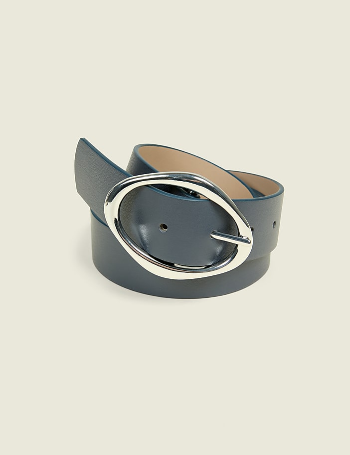 A blue leather belt with a silver oval buckle is laid out on a pale yellow background.