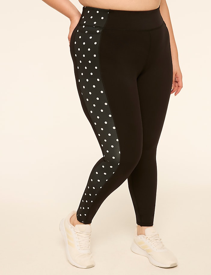 Black leggings with a polka dot side panel are worn by a person standing against a plain, light-colored background.