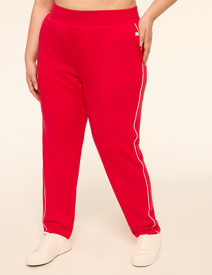 A person wearing red sweatpants with white trim stands against a plain, light-colored background.