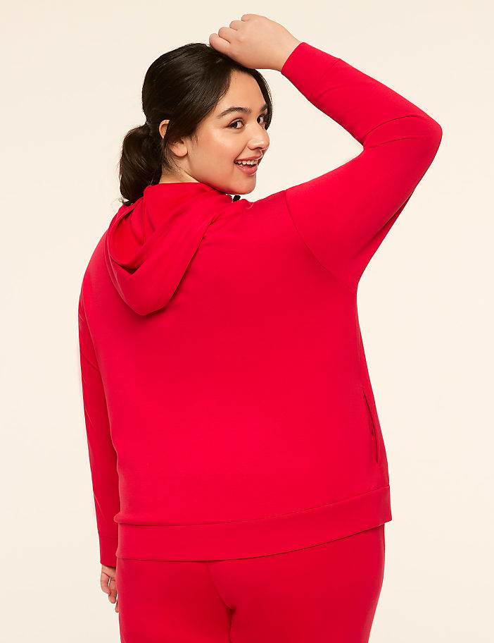 A woman in a red hoodie and pants poses against a plain, light-colored background.
