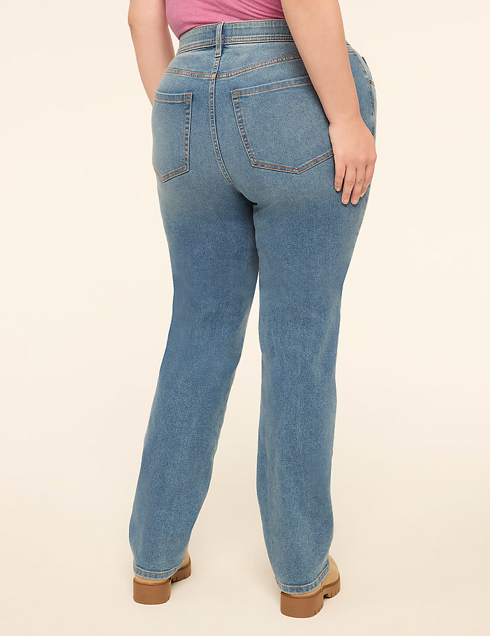 A person wearing light-wash denim jeans and tan platform shoes stands against a plain, light-colored background.