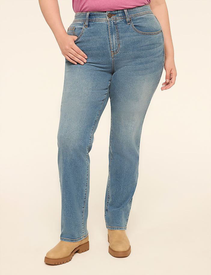A person in light blue jeans and tan platform shoes stands against a plain cream background.