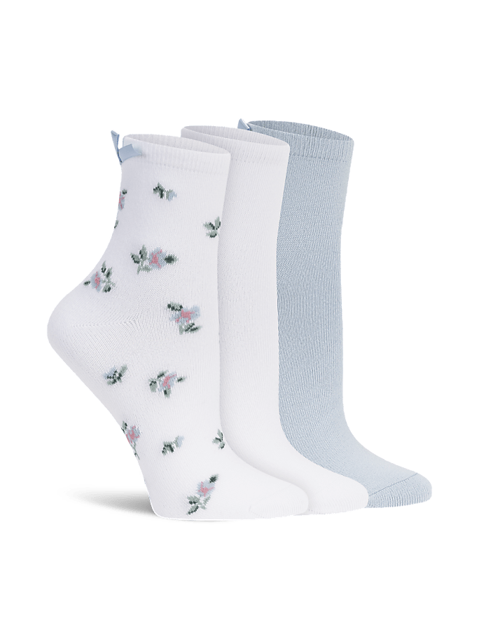 Three pairs of socks, one with a floral pattern and a blue bow, stand in the foreground against a plain white background.