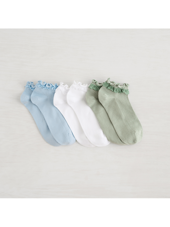 A row of pastel-colored ankle socks with ruffled tops rests on a light wooden surface.