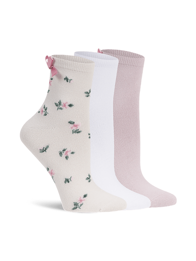 Three pairs of socks, one with a floral pattern and a pink bow, stand in the foreground against a plain white background.