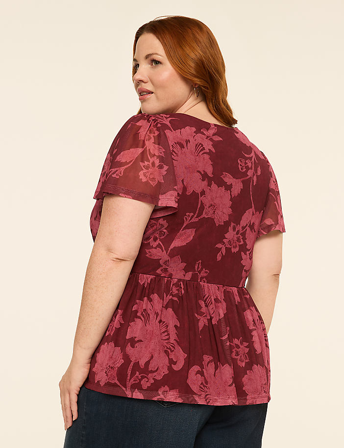 A person wearing dark wash wide-leg jeans stands against a plain, light-colored background.