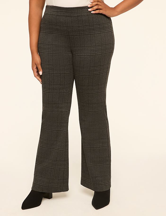 A person in plaid flared pants and black boots stands against a plain, light-colored background.