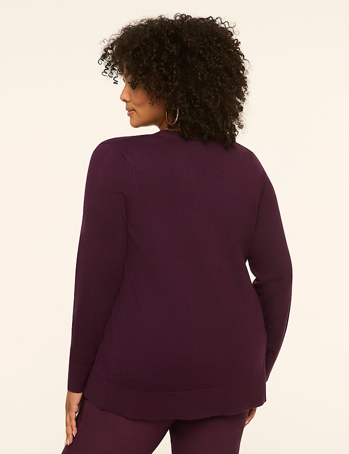 A woman in a plum-colored sweater and pants stands against a plain, light-colored background.