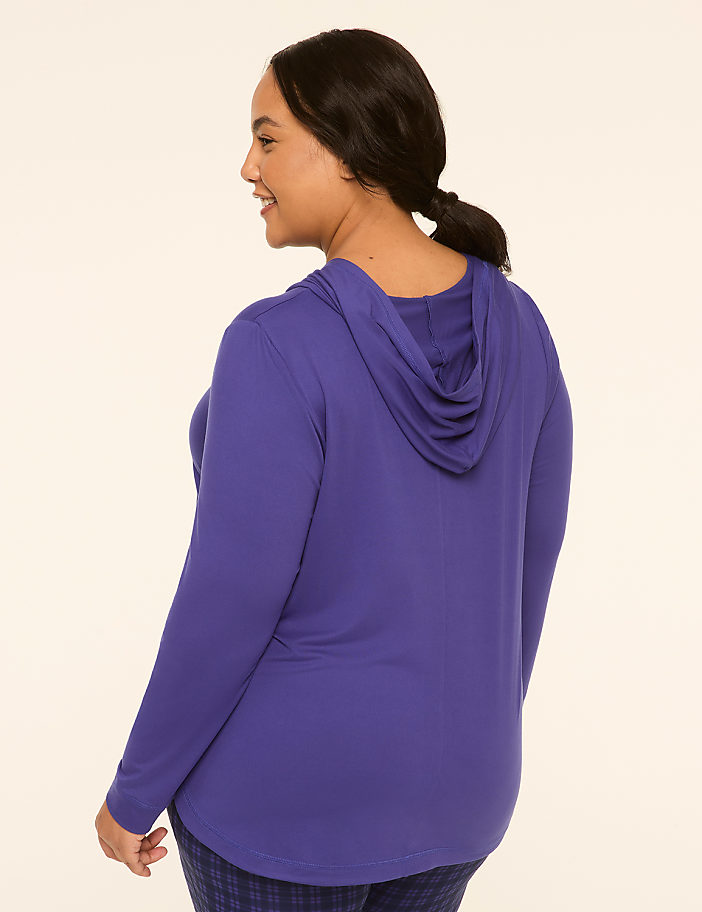 A woman in a purple hoodie stands against a plain, light-colored background.