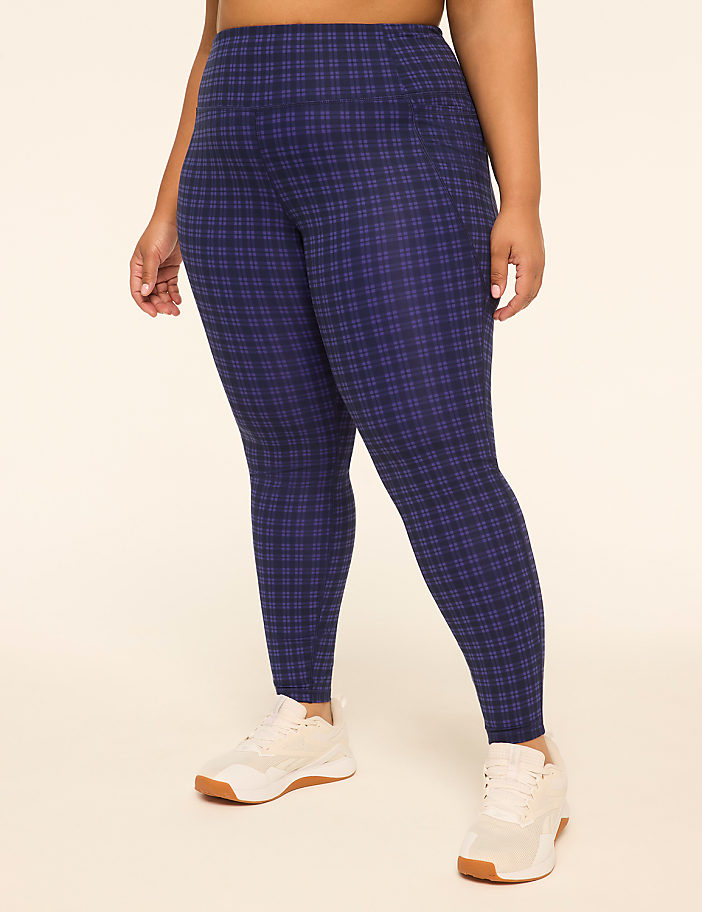 A person wearing blue plaid leggings and white sneakers stands against a plain, light-colored background.